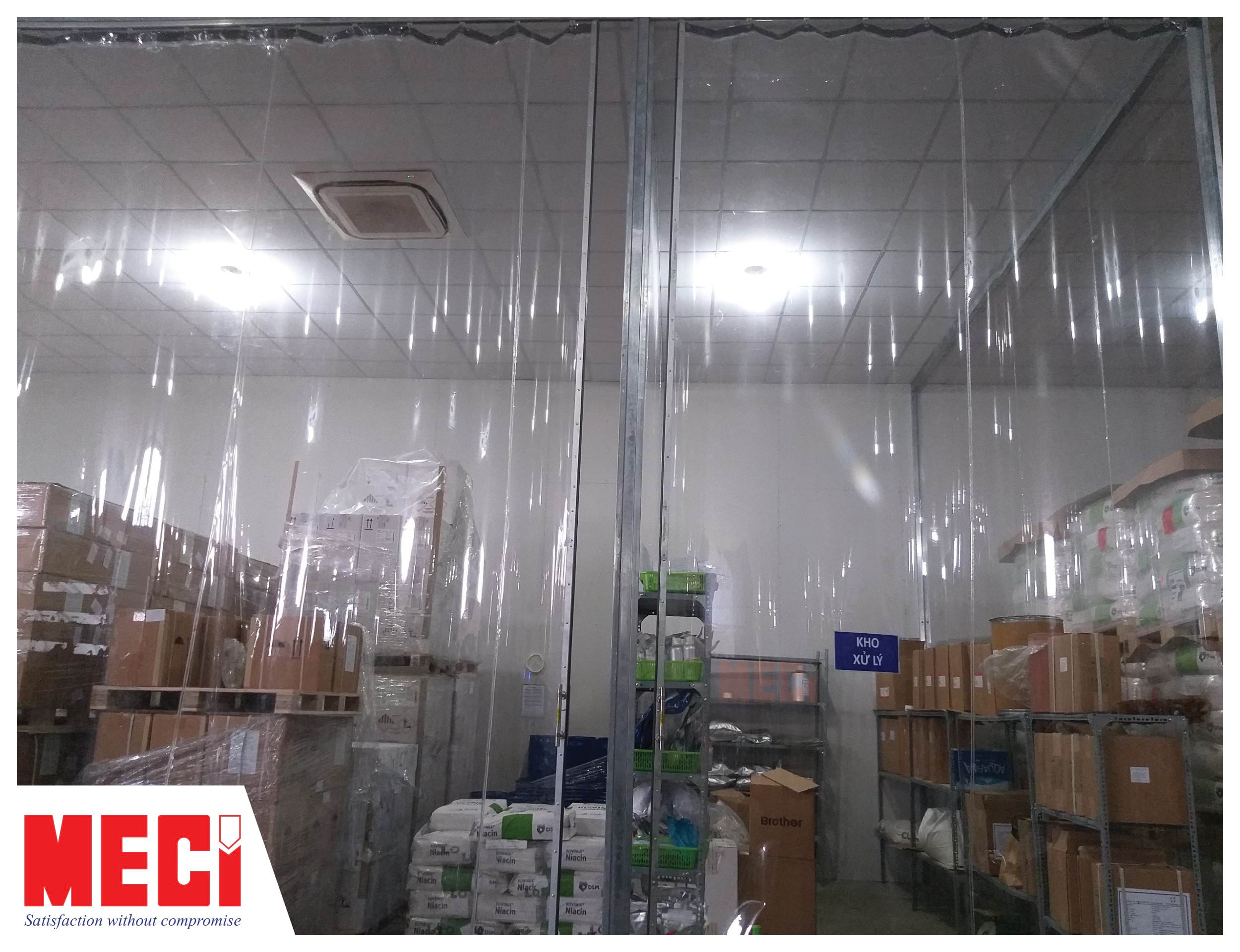 Màn nhựa PVC khổ lớn, trong suốt, có thanh tay cầm lắp đặt tại kho xử lý. Trong kho có rất nhiều hàng hóa.