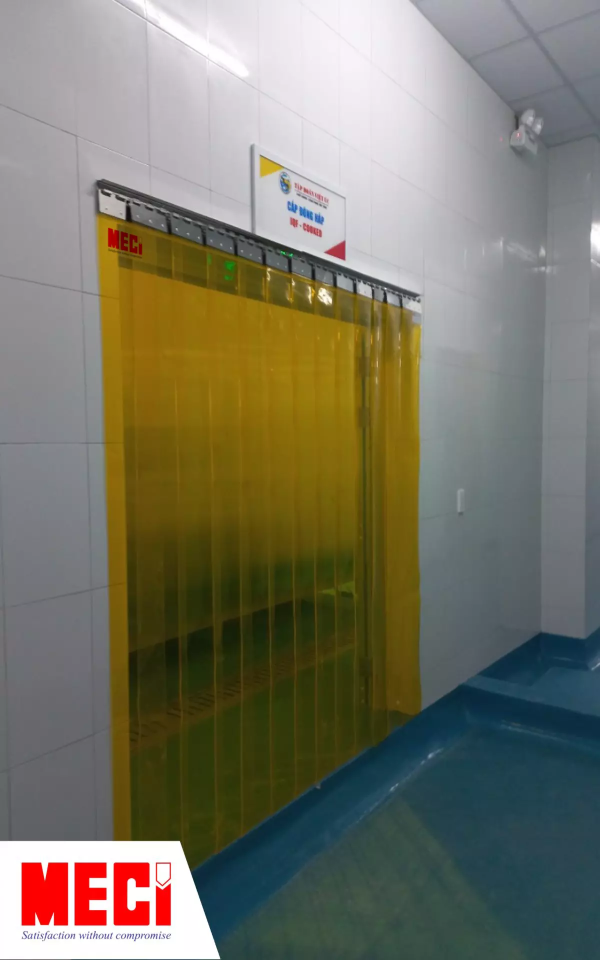 1 cái rèm nhựa PVC màu vàng được lắp trước lối vào, phía trên có biển hiệu phòng cấp đông hấp