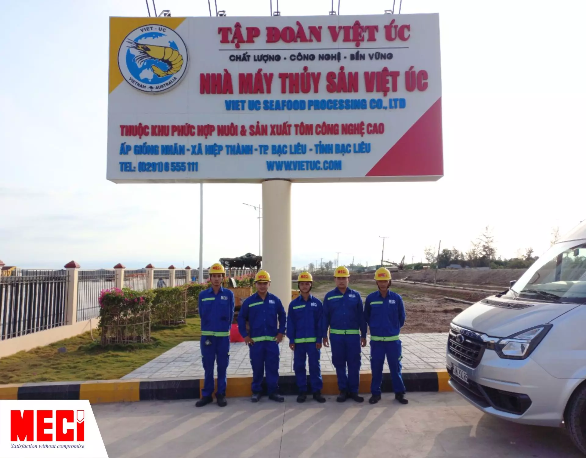 Các kỹ thuật viên MECI đứng trước cổng nhà máy thuỷ sản Việt Úc