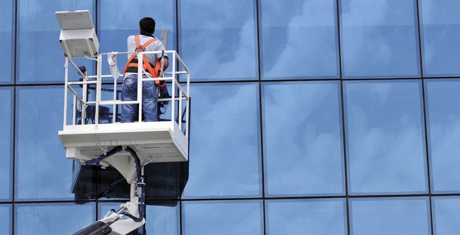 Nhân viên vệ sinh đang lau kính toà nhà ngoài trời.