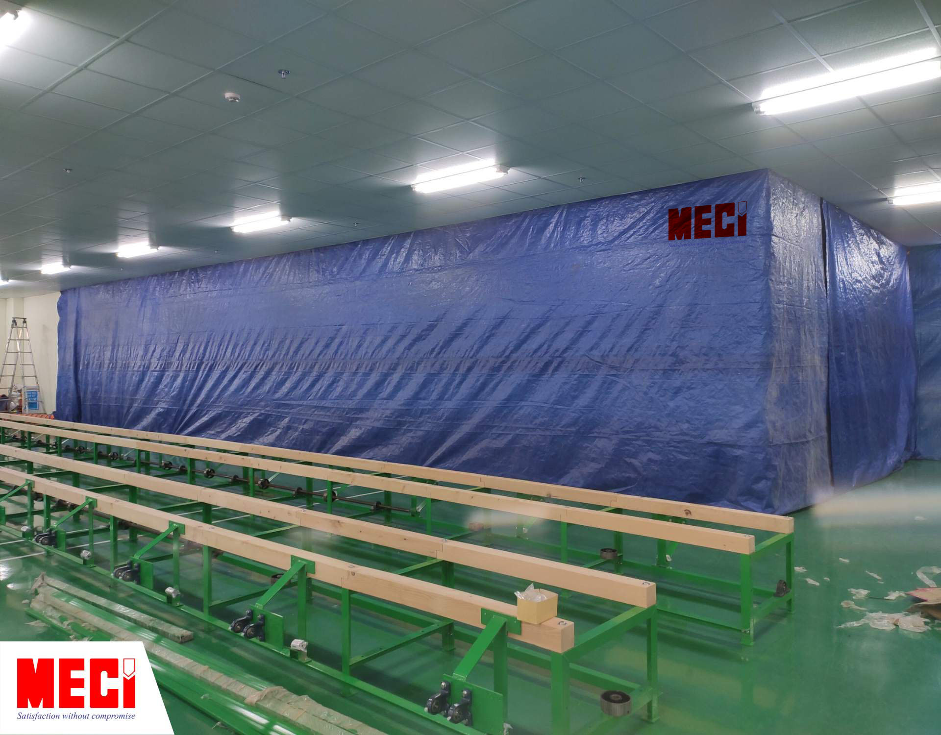 bạt che màu xanh đang bao quanh một khu vực như một căn phòng, rất kín đáo, bên ngoài phòng sạch có thiết bị sản xuất