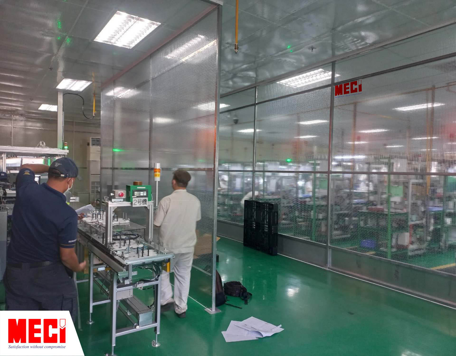 hai người đàn ông bên trong nhà máy sản xuất linh kiện điện tử, có một vách ngăn nhựa Polyester ngăn giữa nhà máy