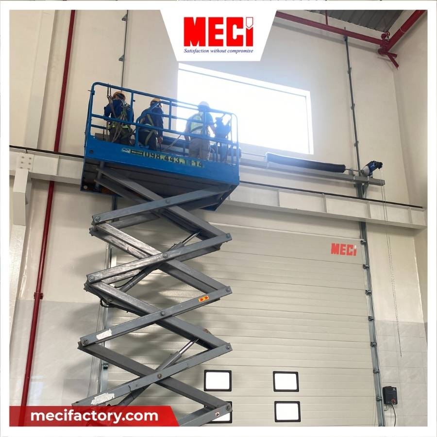 Kỹ thuật MECI đang đứng trên xe nâng để lắp đặt cửa trượt trần thẳng đứng