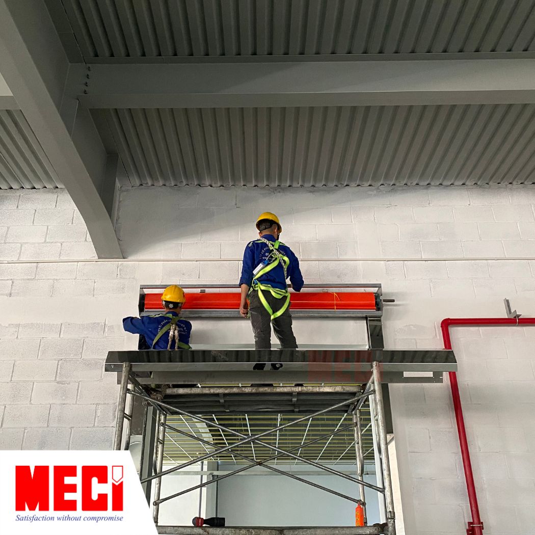 Kỹ thuật MECI đang thi công cửa cuốn nhanh PVC màu đỏ với đầy đủ đồ bào hộ